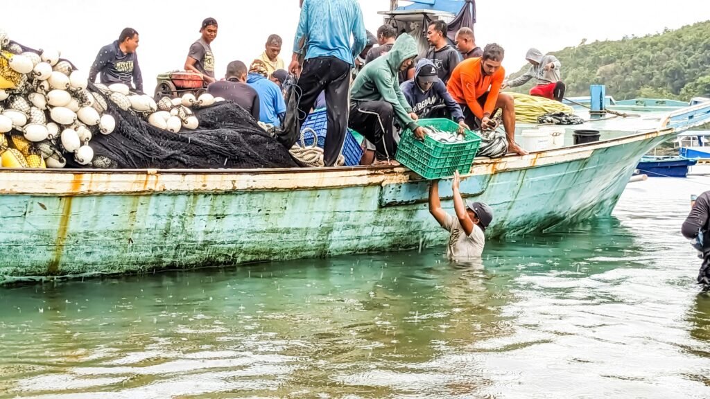 a group of people standing on a boat filled with vegetables